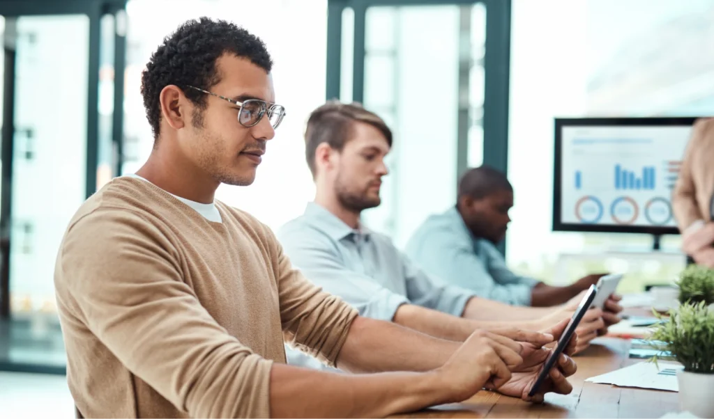 Photo of several men working in office environment on tablet devices. Photo of several men working in office environment on tablet devices.
